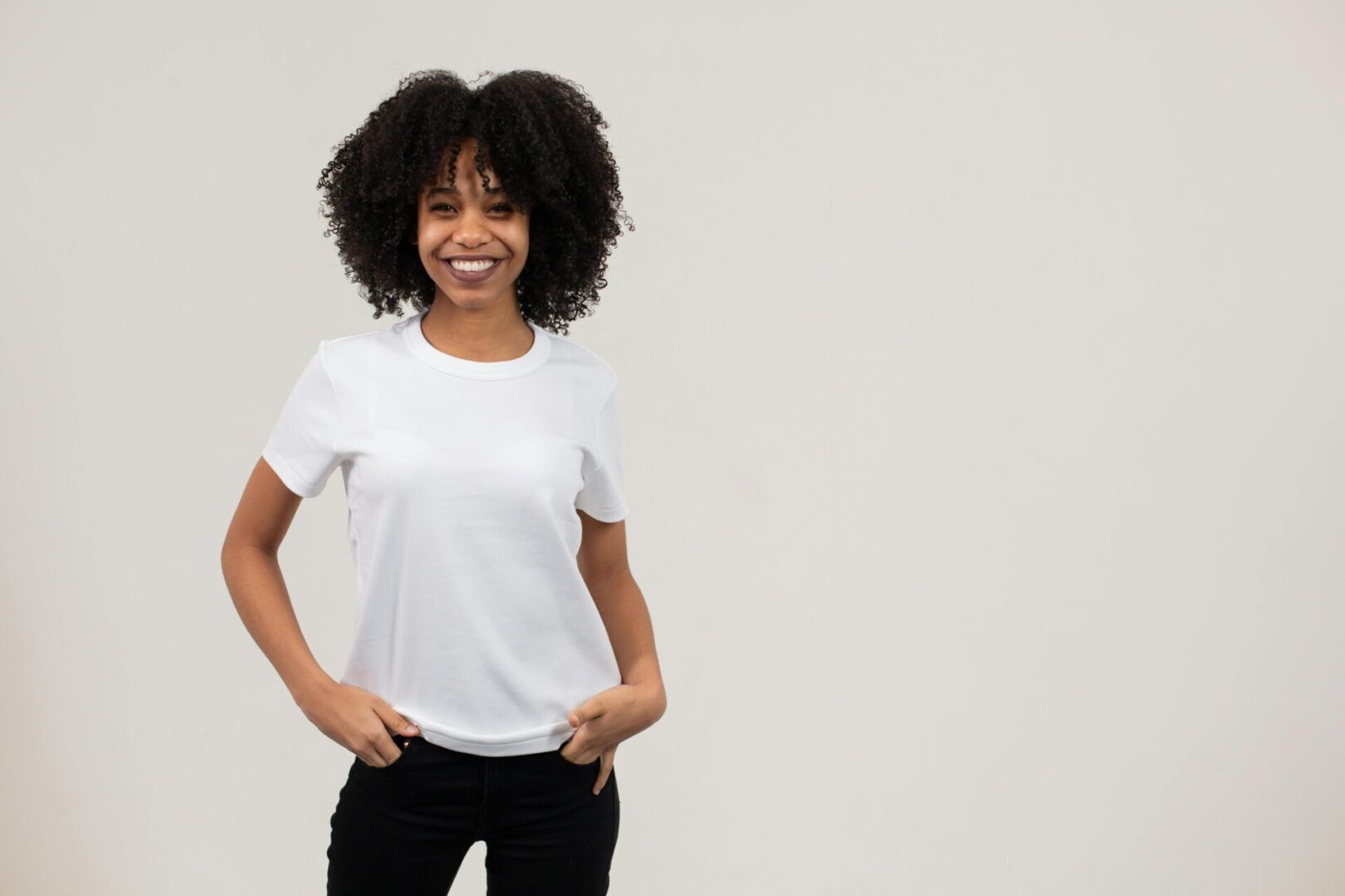 A woman with afro hair wearing white shirt and black pants.